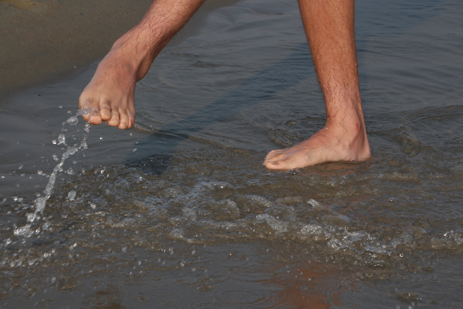 Some feets play with the water at the beach