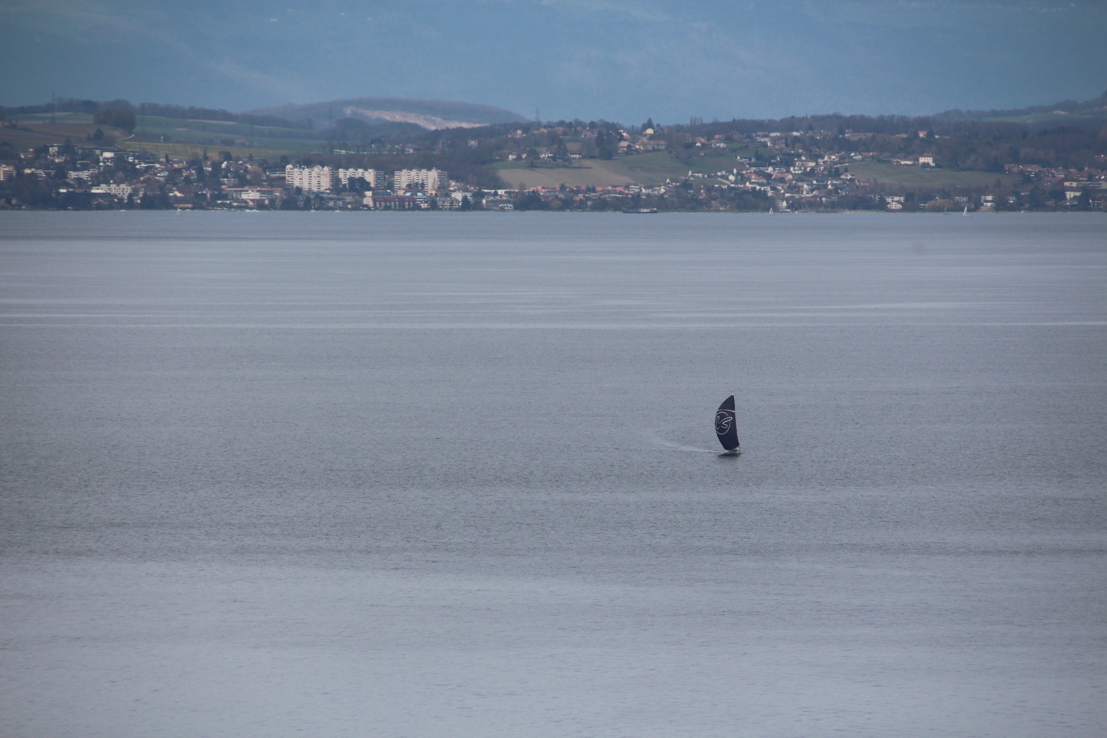 Lonely sailboat on Lake of Geneva with the Swiss coast in the background